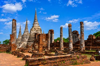 Ancient temple ruins with tall spires under a bright blue sky.