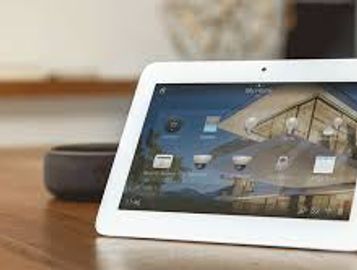Tablet displaying a home automation security interface on a wooden table.