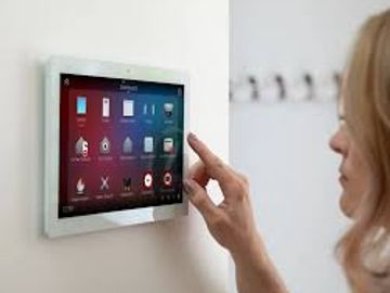 Woman using a wall-mounted touchscreen control panel.