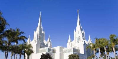 Bright white temple with tall spires under a clear blue sky.