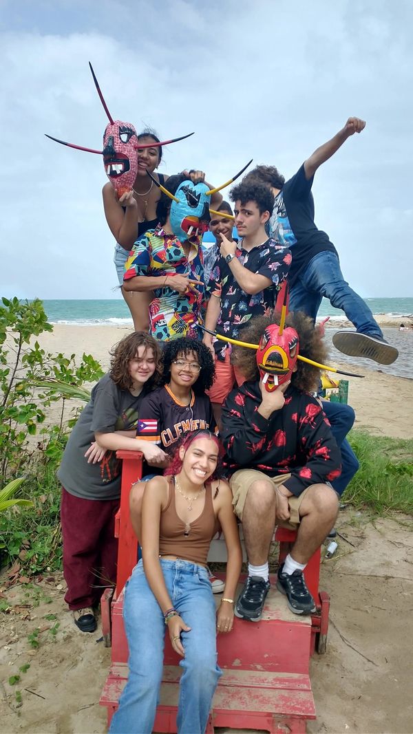 Group of friends on a beach with colorful masks and casual outfits, enjoying a lively moment.