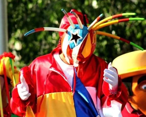 Person in vibrant, colorful costume with a star-shaped mask and tentacle-like extensions.