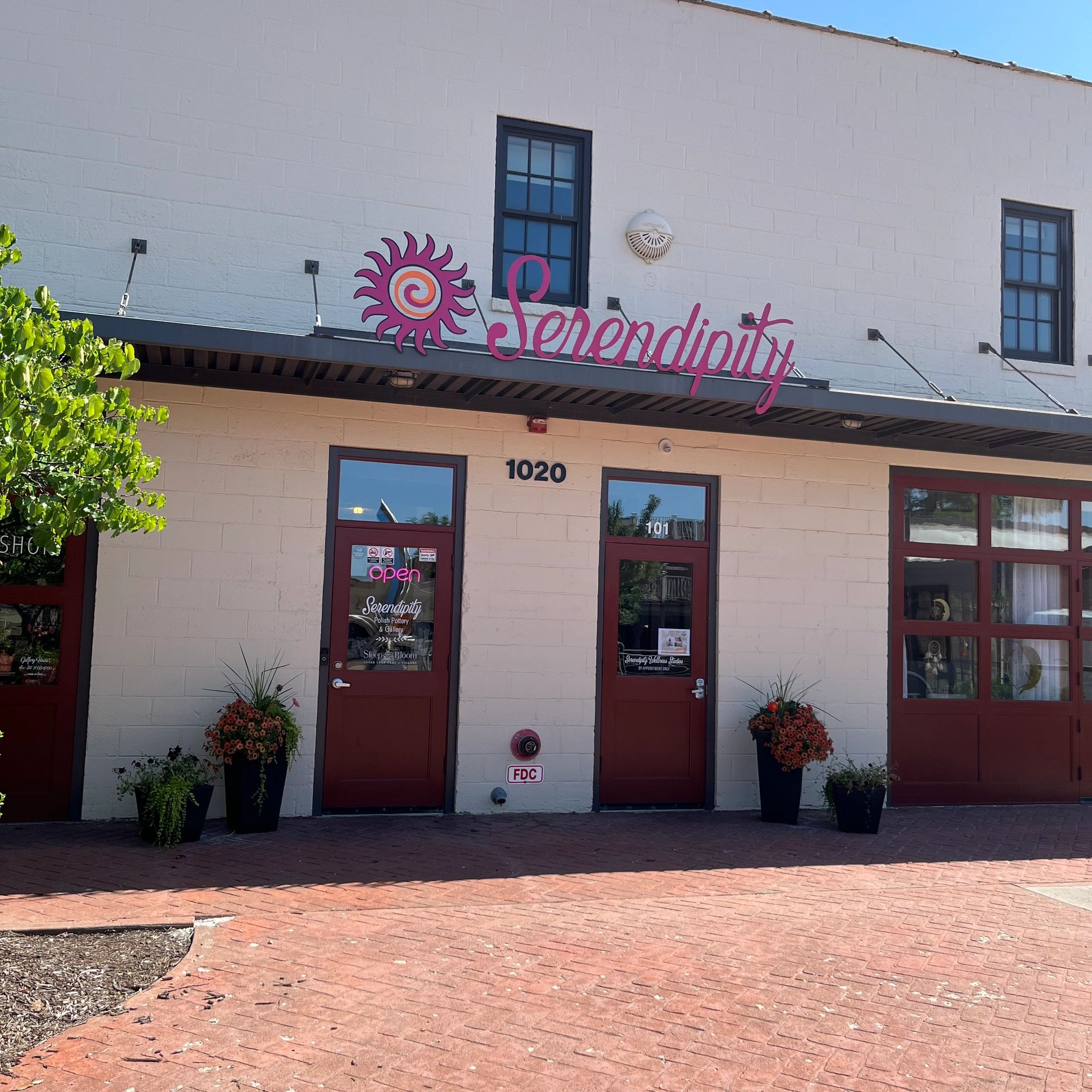 Exterior of Serendipity with two red doors and a bright sign.