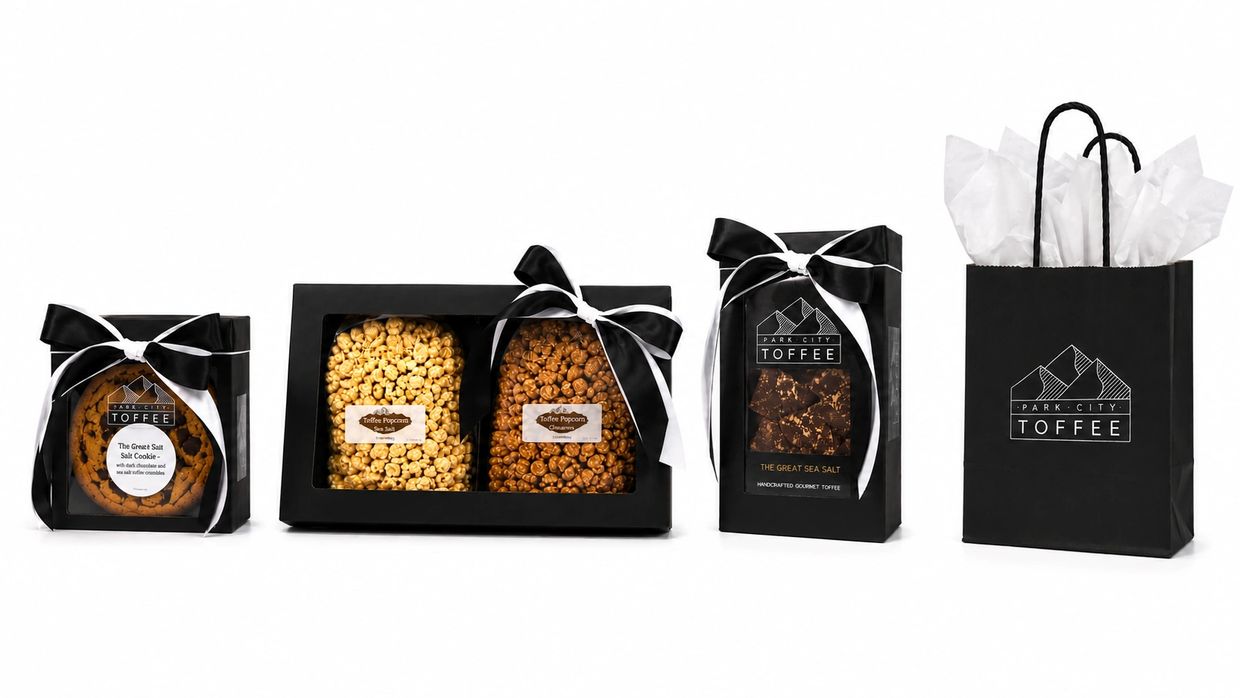 Elegant black gift packaging with toffee, popcorn, and cookies tied with black and white ribbons.