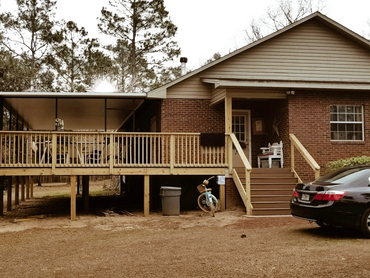 Deck with wooden handrails and a set of eight-step stairway. The deck is custom wrap-around deck