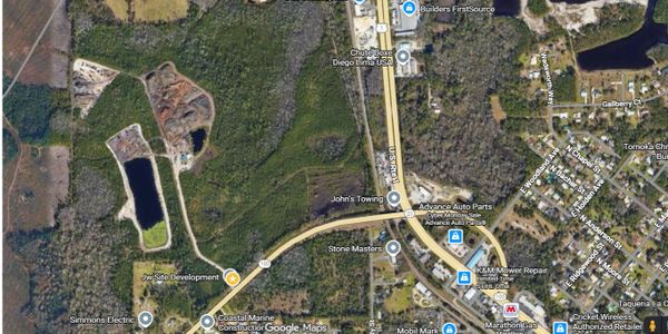 Aerial view of a semi-rural area with roads, businesses, and green spaces.