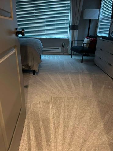 A neatly cleaned bedroom with patterned carpet and closed blinds.