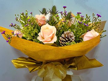 Soft pastel roses with fircones, thistles and festive foliage.