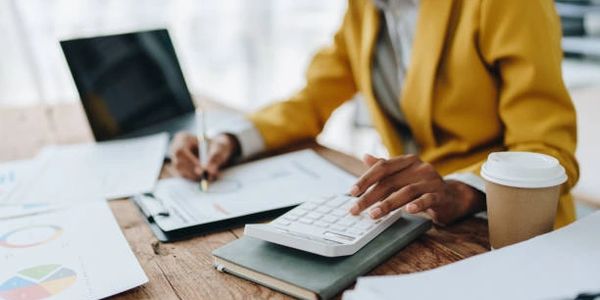 Person working with calculator and documents at a desk.