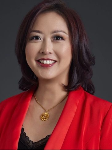 Professional woman smiling in a red blazer with gold necklace.