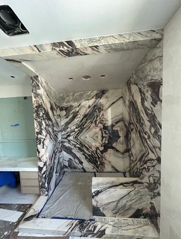 Luxurious bathroom under construction with striking marble walls and flooring.