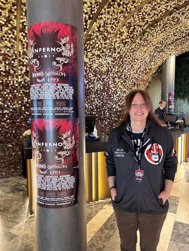 Person standing next to Inferno 2023 event posters on a column.