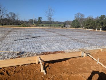 Construction site with concrete base and rebar grid under clear sky.