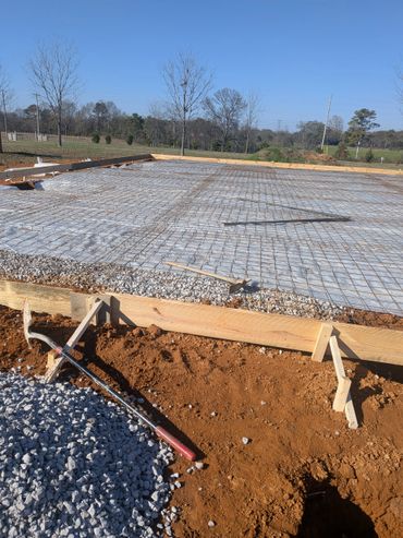 Construction site with foundation rebar and wooden framing under clear blue sky.