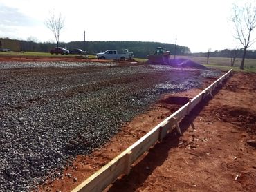 Construction site with gravel and wooden framing for a foundation.
