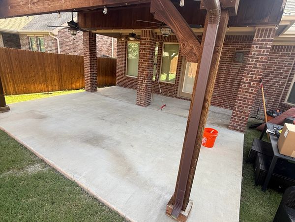 Covered concrete patio with fan and orange bucket.