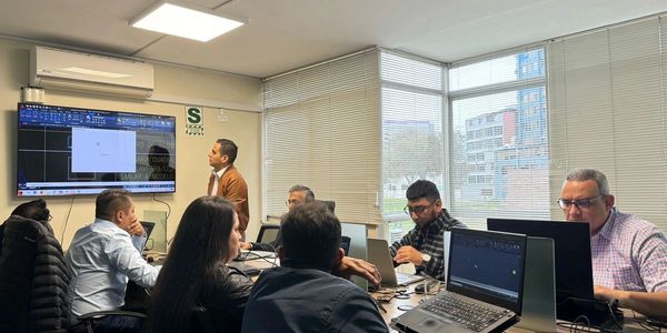 A group of professionals working in an office meeting with computer screens.
