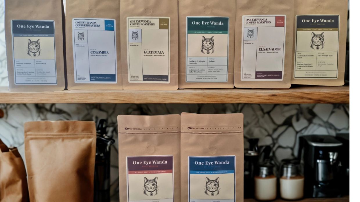 Various One Eye Wanda coffee bags arranged on wooden shelves.