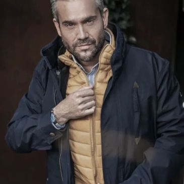 Confident man wearing layered jackets, adjusting his inner yellow vest.
