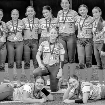 A girls' softball team posing proudly with medals after a game.
