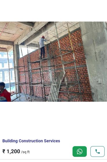 Construction worker on scaffolding building a brick wall.