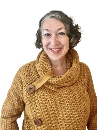 Smiling woman in a mustard yellow knitted sweater.