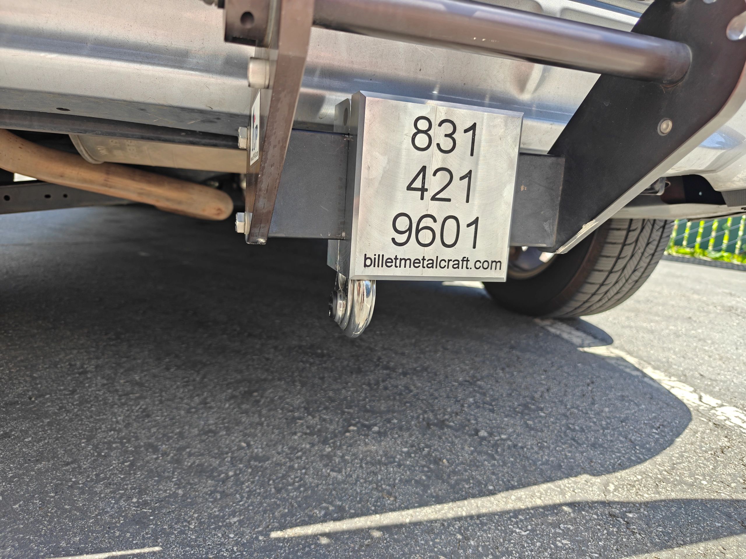 Close-up of a metal hitch with contact info under a vehicle.