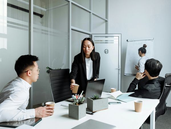 Colleagues collaborating in a modern office meeting room with laptops and notes.