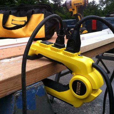 Yellow Stanley Fatmax power strip clamped to a wooden workbench with tools nearby.