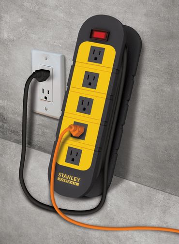 Stanley FatMax power strip plugged in with two cords, mounted on a concrete wall.
