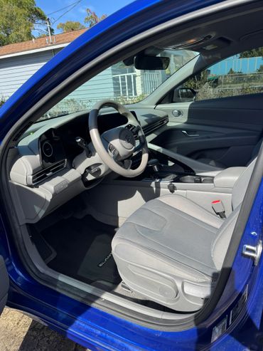 Interior view of a blue Hyundai Elantra with light gray seats and modern dashboard.