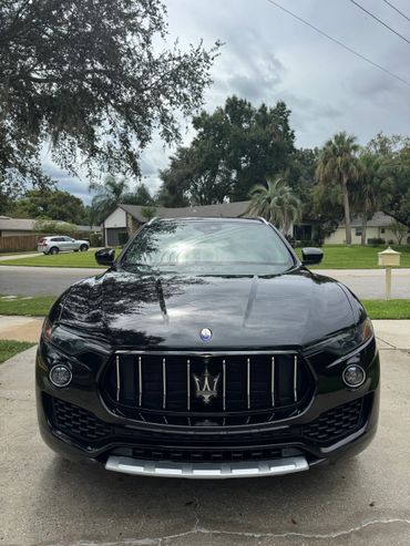 Front view of a black Maserati SUV in a residential driveway.