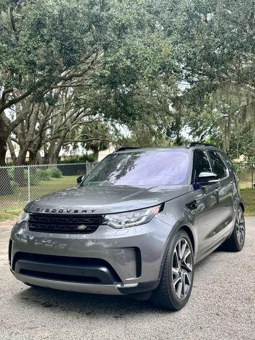 Gray Land Rover Discovery parked on a tree-lined street.