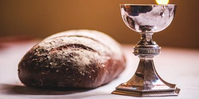 A loaf of bread and a silver chalice on a table.