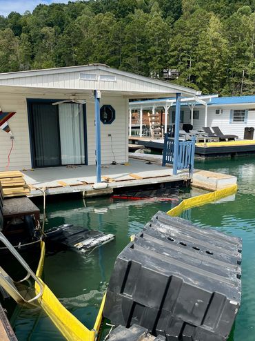 Floating dock with visible damage and water around it near a lakeside cabin.