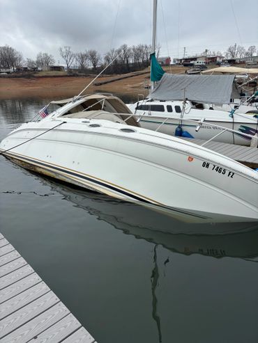 A white boat partially submerged in water at a dock on a cloudy day.