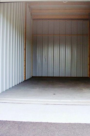 Inside storage unit showing wood/steel construction, cement floor, and 2' overhang