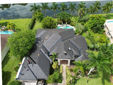 Workers installing a new roof on a large house surrounded by greenery and a pool.
