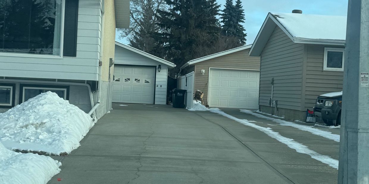 Snowy suburban driveways leading to garages on a clear winter day.