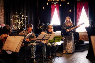 Ashlee leads the class from her guitar and sings along while the students play.