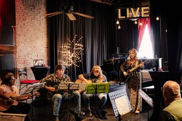 Ashlee is looking on three of her guitar students as we all play along together.