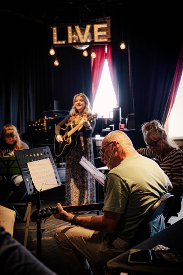 Ashlee is playing and singing along with her guitar class in this picture