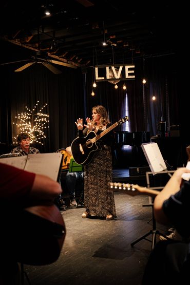 This is a picture of Ashlee Elmore teaching her guitar class. She’s holding up her fingers