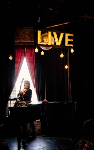 This is a picture of Ashlee Elmore wearing her Guitar standing near the window