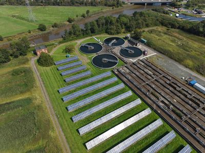 Aerial drone view of a commercial solar panel installation and nearby infrastructure in Scotland.