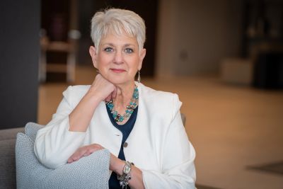Confident woman with short white hair in white blazer.