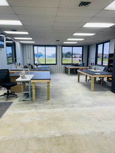 Spacious sewing workshop with multiple machines and a person working.