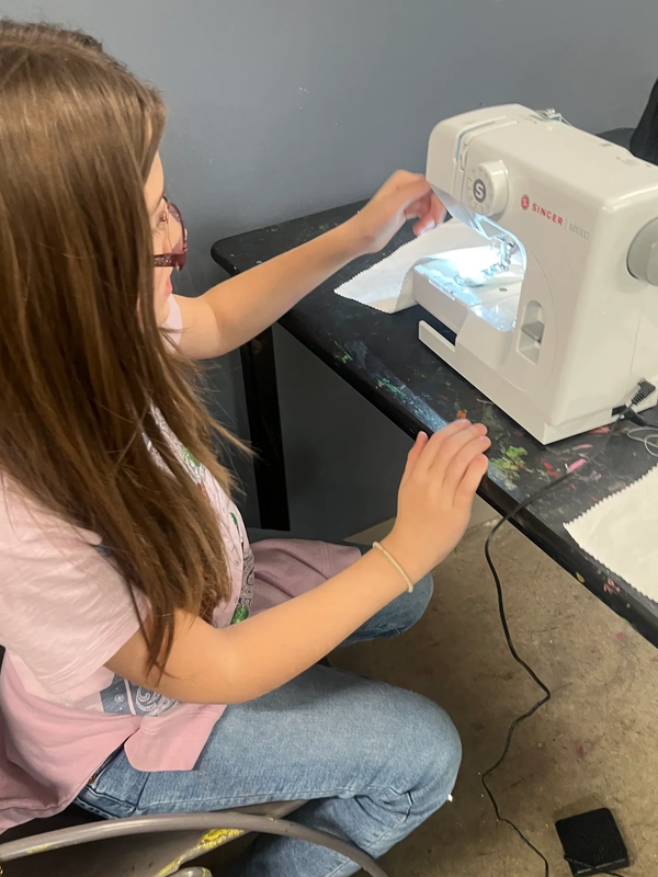Girl using a sewing machine on fabric.