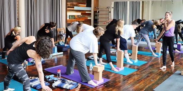 A group yoga class practicing with blocks and mats indoors.