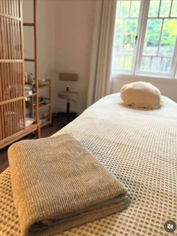 Cozy treatment room with folded towel on bed.